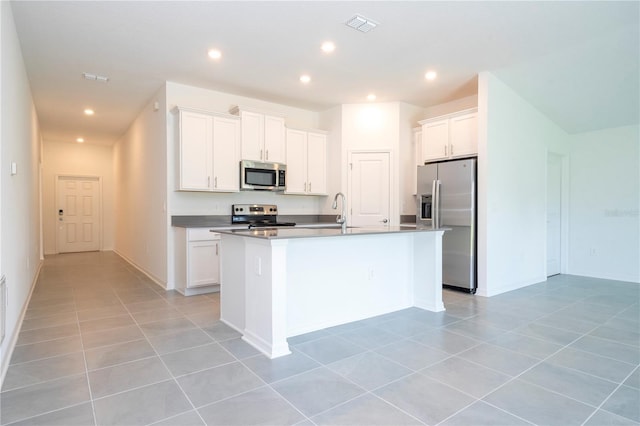 kitchen featuring light tile patterned floors, sink, appliances with stainless steel finishes, a kitchen island with sink, and white cabinets