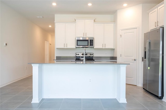 kitchen featuring light tile patterned floors, stainless steel appliances, an island with sink, and white cabinets