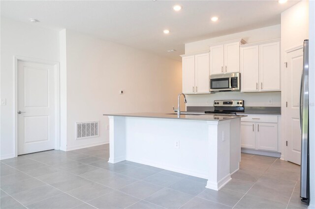 kitchen with appliances with stainless steel finishes, sink, a center island with sink, and white cabinets