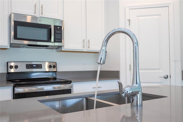 kitchen with sink, white cabinets, and appliances with stainless steel finishes