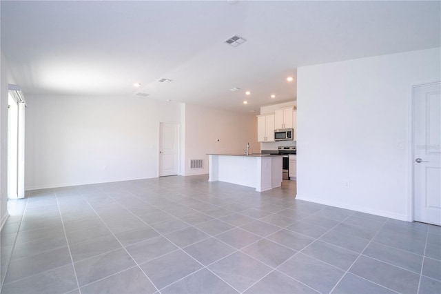 unfurnished living room with sink, vaulted ceiling, and light tile patterned floors