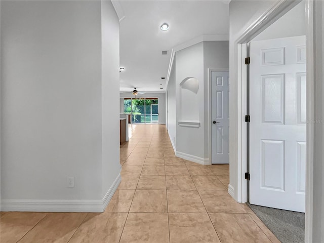 hallway with light tile patterned flooring and crown molding