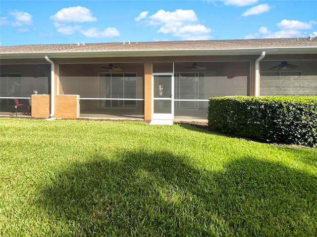 rear view of house featuring ceiling fan, a sunroom, and a lawn