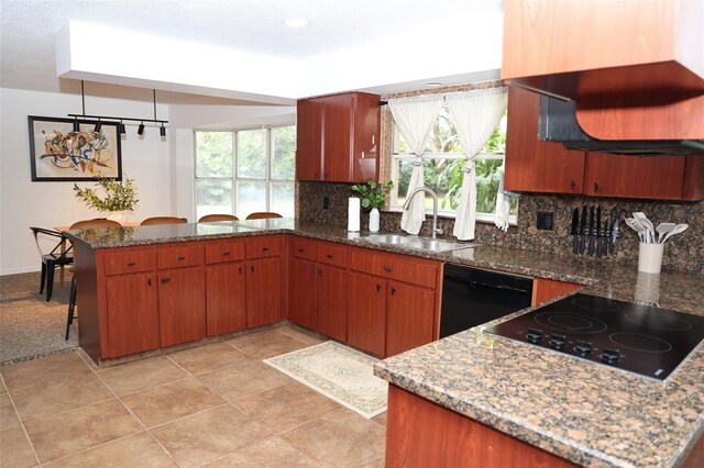 kitchen featuring kitchen peninsula, pendant lighting, sink, dark stone counters, and black appliances