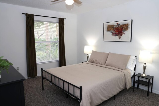 bedroom featuring ceiling fan, multiple windows, and dark carpet