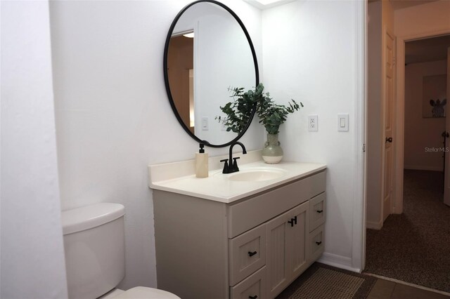 bathroom with toilet, tile patterned flooring, and vanity