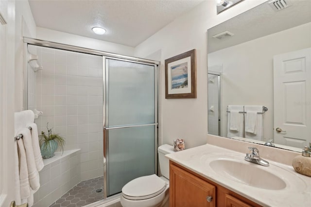 bathroom featuring a textured ceiling, a shower with shower door, vanity, and toilet