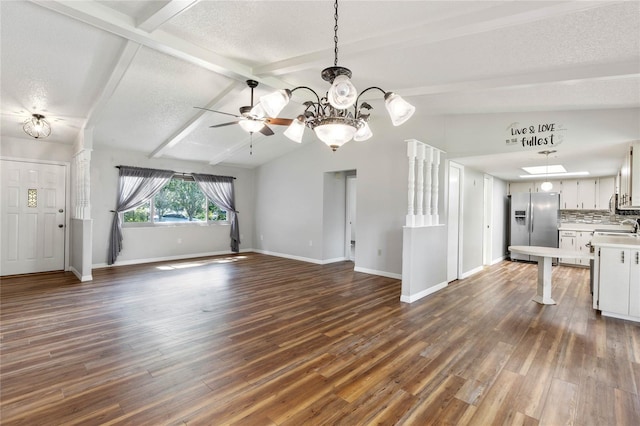 unfurnished living room with ceiling fan with notable chandelier, a textured ceiling, dark hardwood / wood-style flooring, sink, and lofted ceiling with beams