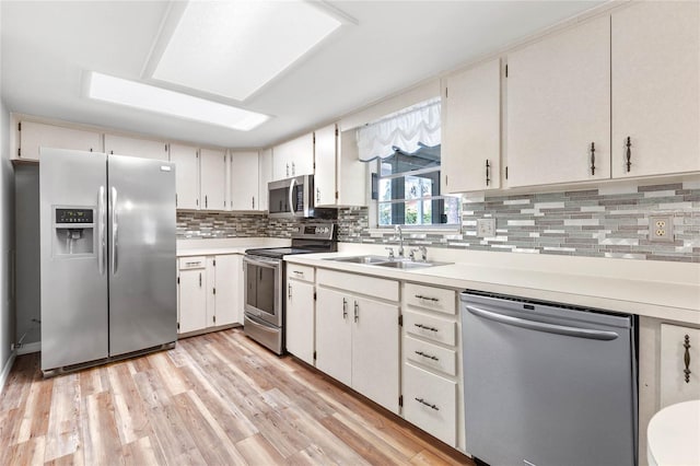 kitchen with tasteful backsplash, light hardwood / wood-style floors, stainless steel appliances, sink, and white cabinets