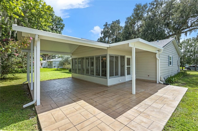 rear view of property with a sunroom, a yard, and a patio area