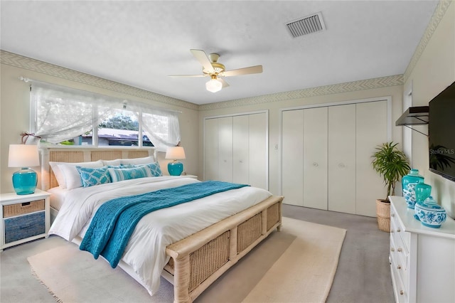 carpeted bedroom featuring two closets and ceiling fan