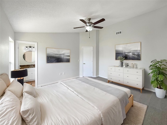 carpeted bedroom with lofted ceiling, ensuite bathroom, ceiling fan, and a textured ceiling