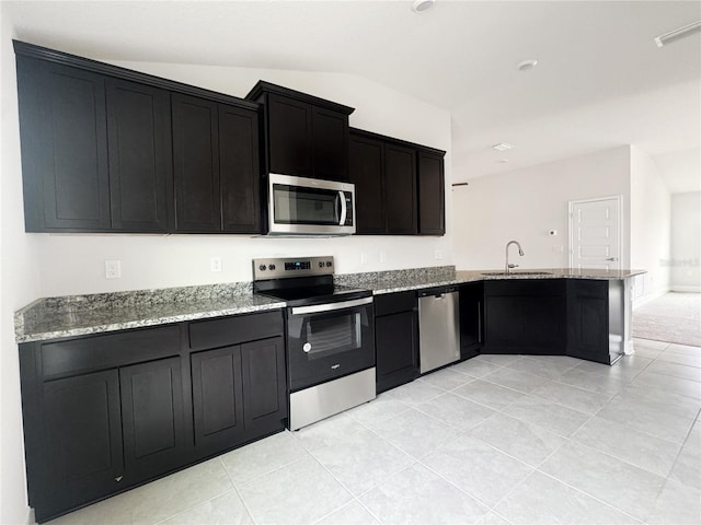 kitchen with kitchen peninsula, sink, appliances with stainless steel finishes, light tile patterned floors, and light stone counters