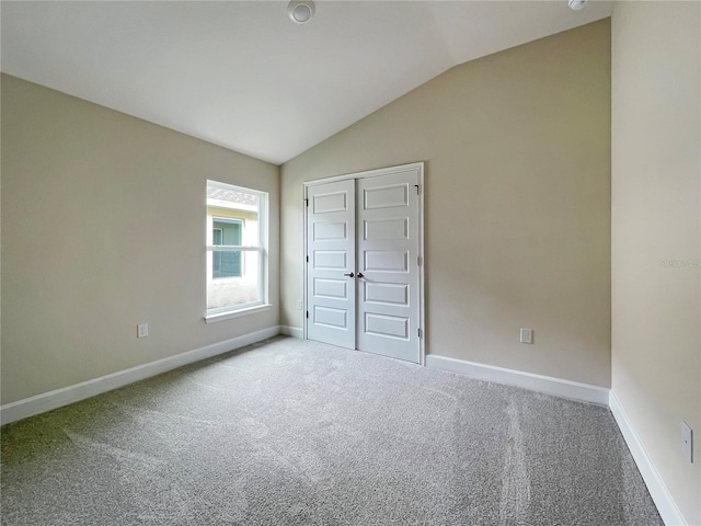 unfurnished bedroom featuring vaulted ceiling, a closet, and carpet floors