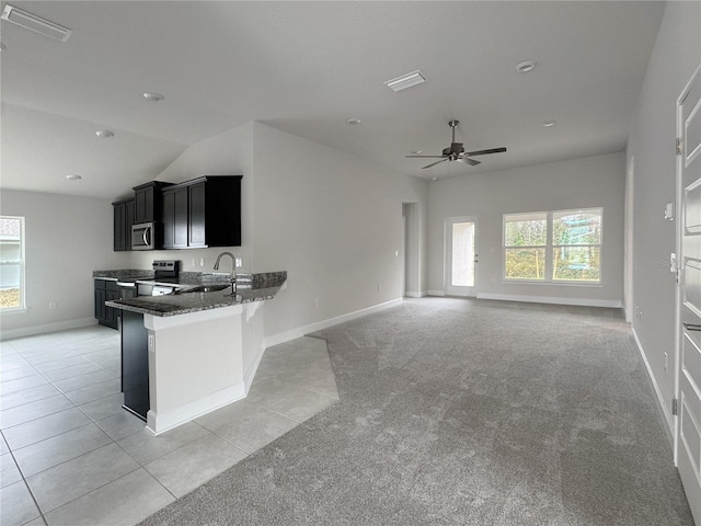 kitchen featuring stone counters, kitchen peninsula, sink, a breakfast bar area, and light carpet