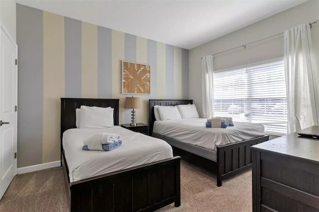 bedroom featuring baseboards, wallpapered walls, and light carpet
