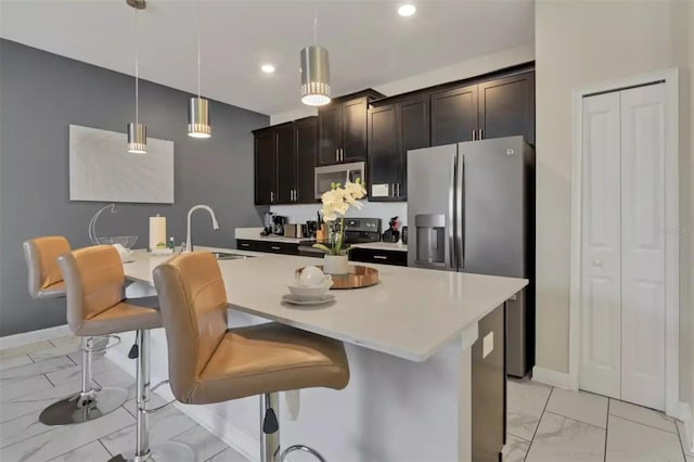 kitchen with a sink, stainless steel appliances, marble finish floor, decorative light fixtures, and light countertops