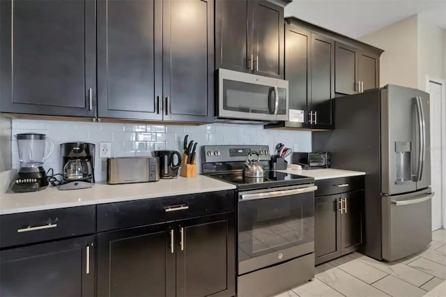 kitchen featuring dark brown cabinetry, decorative backsplash, appliances with stainless steel finishes, and light tile patterned floors