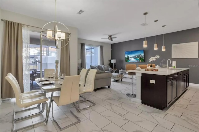 tiled dining space with sink and ceiling fan with notable chandelier