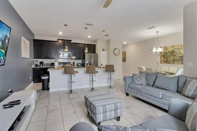 living area with recessed lighting, marble finish floor, an inviting chandelier, and baseboards