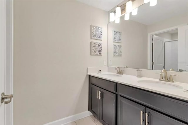 bathroom featuring double vanity, baseboards, a stall shower, and a sink