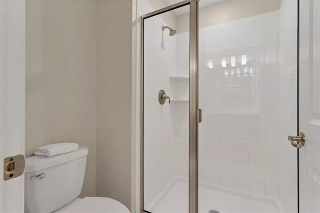 bathroom with a shower with shower door and toilet