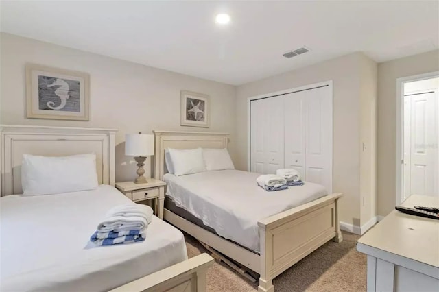 bedroom featuring light colored carpet, visible vents, a closet, and baseboards