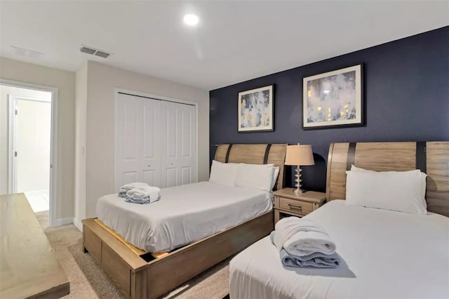bedroom featuring baseboards, visible vents, a closet, and light colored carpet