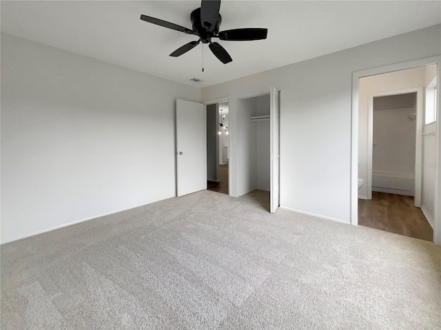 unfurnished bedroom with light carpet, connected bathroom, a closet, and ceiling fan