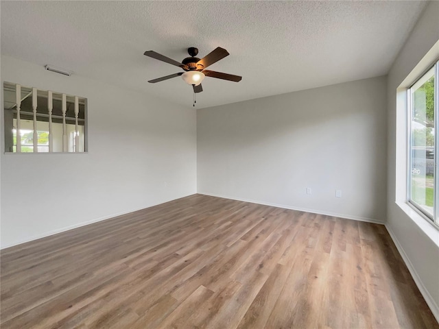 empty room with ceiling fan, light hardwood / wood-style flooring, and a textured ceiling