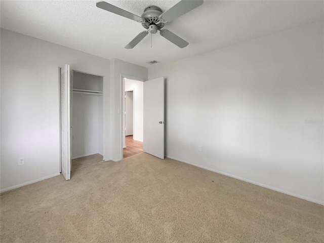 unfurnished bedroom featuring ceiling fan, light carpet, and a closet