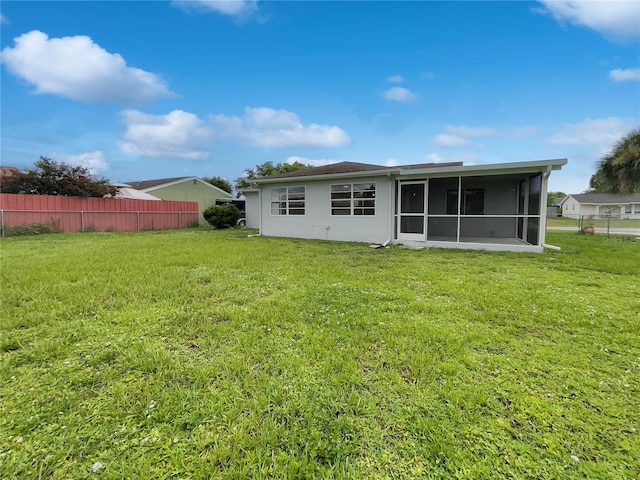 rear view of property with a lawn and a sunroom