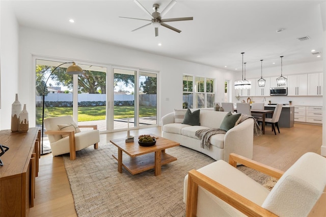 living room with plenty of natural light, ceiling fan, and light wood-type flooring