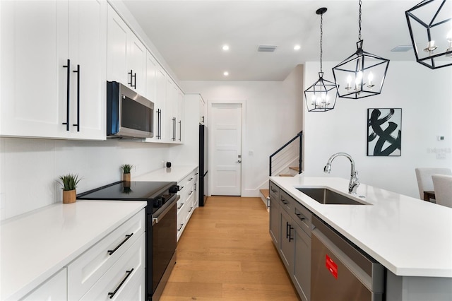 kitchen with stainless steel appliances, hanging light fixtures, and white cabinets