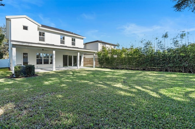 rear view of house featuring a lawn and a patio