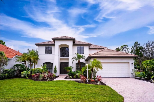 mediterranean / spanish house featuring a garage and a front lawn