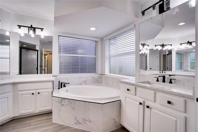 bathroom featuring vanity, tiled tub, and hardwood / wood-style floors