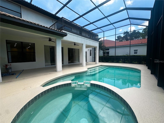 view of swimming pool featuring a patio area, an in ground hot tub, ceiling fan, and glass enclosure