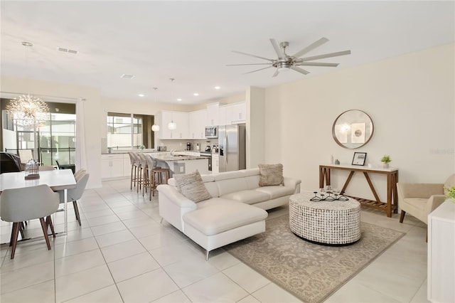 living room featuring ceiling fan with notable chandelier and light tile patterned floors