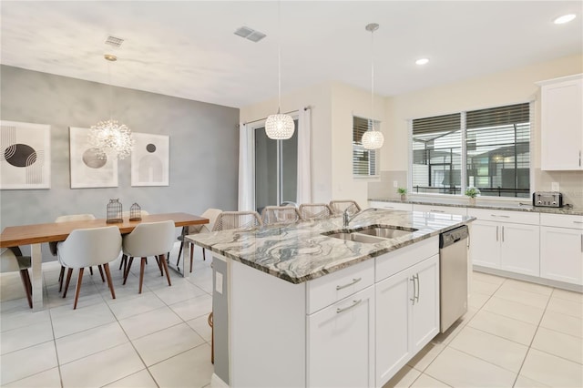 kitchen featuring pendant lighting, sink, dishwasher, light stone counters, and a kitchen island with sink