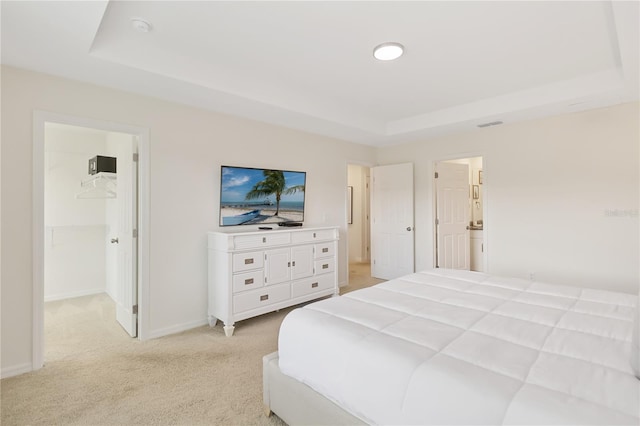 carpeted bedroom featuring a walk in closet and a tray ceiling