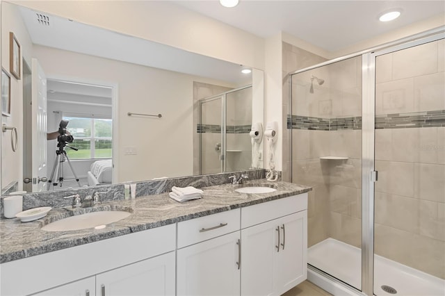 bathroom featuring a shower with shower door and dual bowl vanity