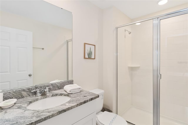 bathroom featuring vanity, a shower with door, and toilet