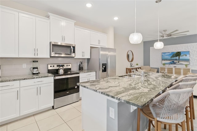 kitchen with appliances with stainless steel finishes, tasteful backsplash, a center island with sink, sink, and white cabinetry