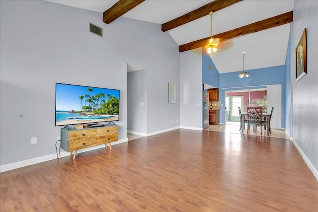 unfurnished living room with high vaulted ceiling, beam ceiling, light hardwood / wood-style floors, and a notable chandelier