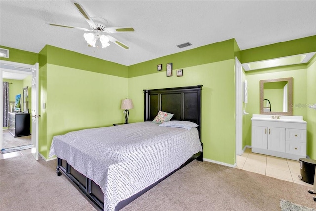 carpeted bedroom with ceiling fan, a textured ceiling, and ensuite bath