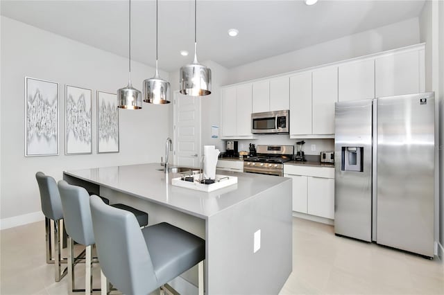 kitchen with appliances with stainless steel finishes, light tile patterned flooring, a center island with sink, and white cabinets