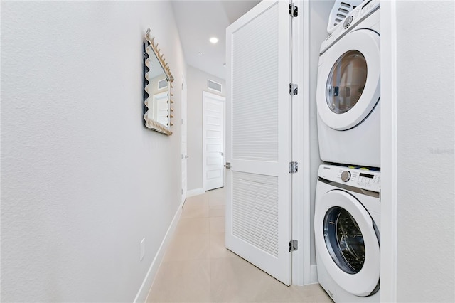 laundry room featuring stacked washer / dryer and light tile patterned floors