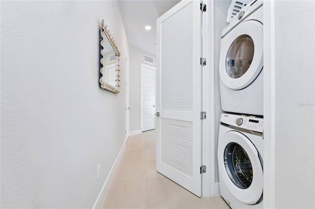 laundry room featuring visible vents, baseboards, light tile patterned floors, laundry area, and stacked washer and clothes dryer