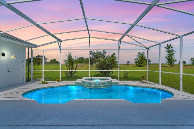 pool at dusk with a lanai, an in ground hot tub, and a lawn